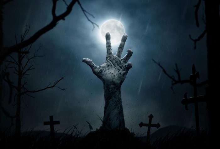 A graveyard with a hand bursting out of the ground. The moon in the background.